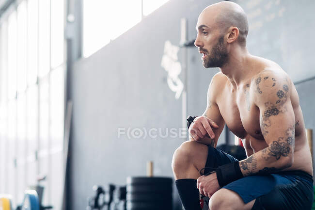 Retrato del hombre tatuado en el gimnasio mirando hacia otro lado - foto de stock