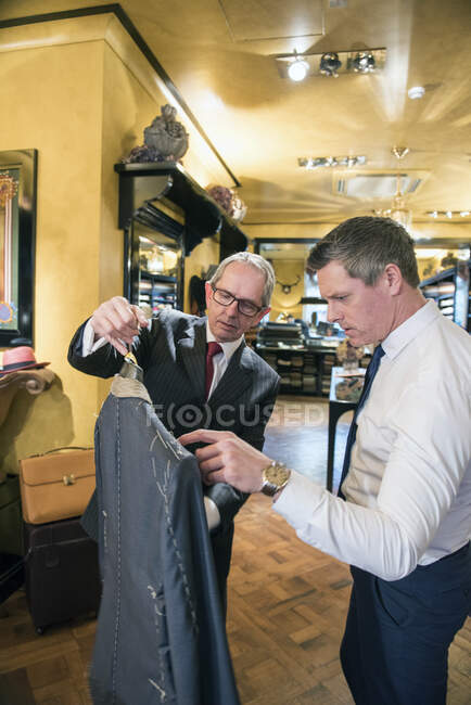 Alfaiate mostrando jaqueta personalizada do cliente na loja de alfaiates — Fotografia de Stock
