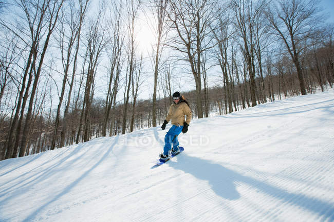 Woman snowboarding in snow caped forest — Stock Photo