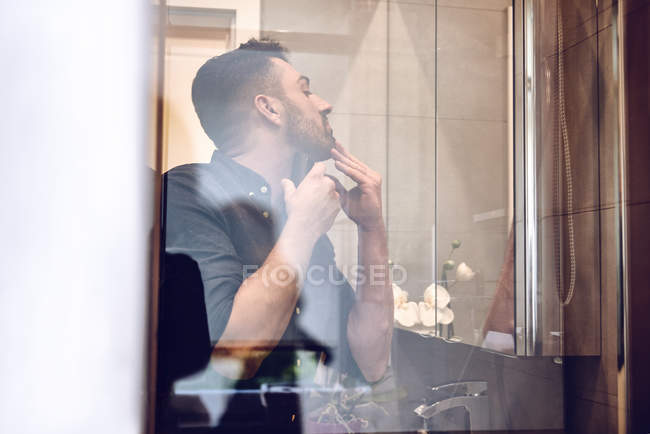 View through glass of man shaving — Stock Photo
