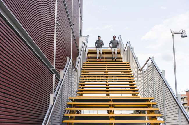 Young male twins running down on city stairway — Stock Photo