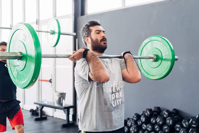 Haltérophilie homme avec haltère en salle de gym — Photo de stock