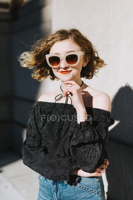 Портрет улыбающейся рыжей женщины в солнечных очках, смотрящей в камеру — стоковое фото