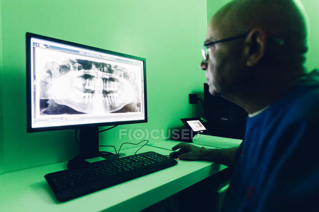 Dentist looking at dental x-ray on computer — Stock Photo