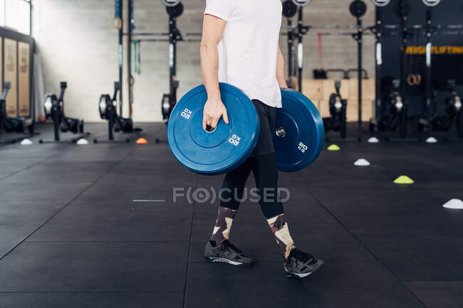 Cropped view of man carrying weight in gym — Stock Photo