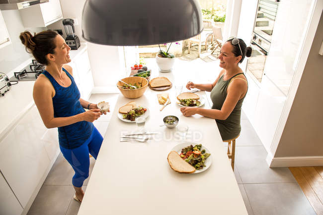 Due amici che si godono il pranzo d'insalata in cucina — Foto stock