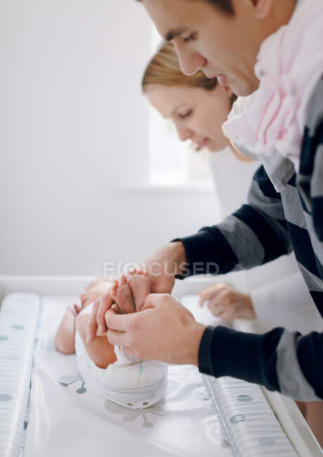 Mother and father dressing newborn baby — Stock Photo