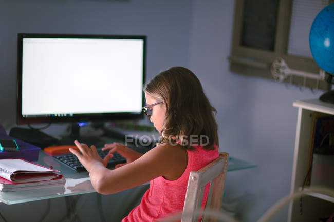 Молодая девушка делает домашнее задание и с помощью компьютера — стоковое фото