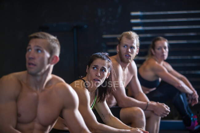 Grupo de personas ejercitándose en el gimnasio, tomando descanso después de usar máquinas de remo - foto de stock