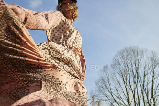 Hippy style woman dancing against blue sky — Stock Photo