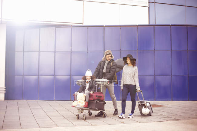 Vista a distanza della ragazza con i genitori che cavalcano sul carrello bagagli — Foto stock