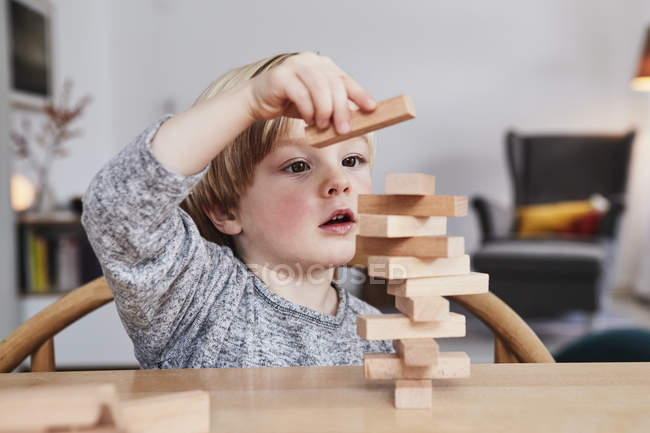 Portrait of young boy building structure with wooden building blocks — Stock Photo
