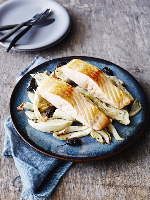 Запеченный лосось с фенхелем и оливками, на голубой тарелке, крупным планом — стоковое фото