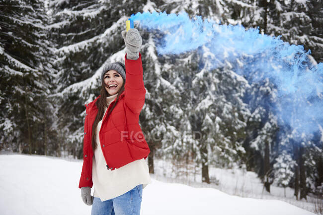 Young woman with smoke flare in snow — Stock Photo