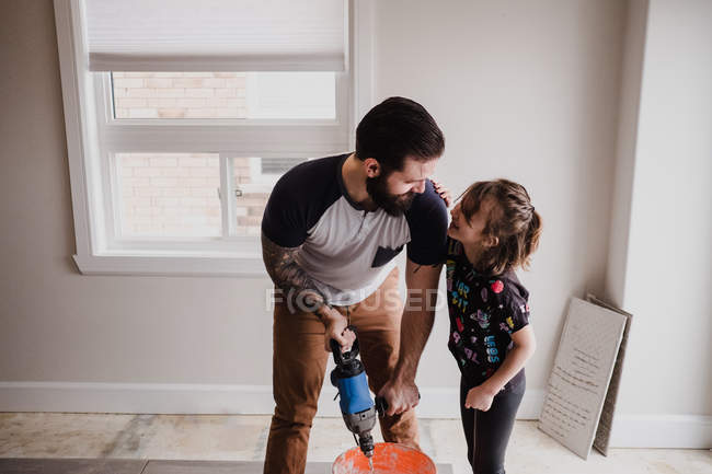 Pai e filha mistura de cimento em balde com misturador de mão — Fotografia de Stock
