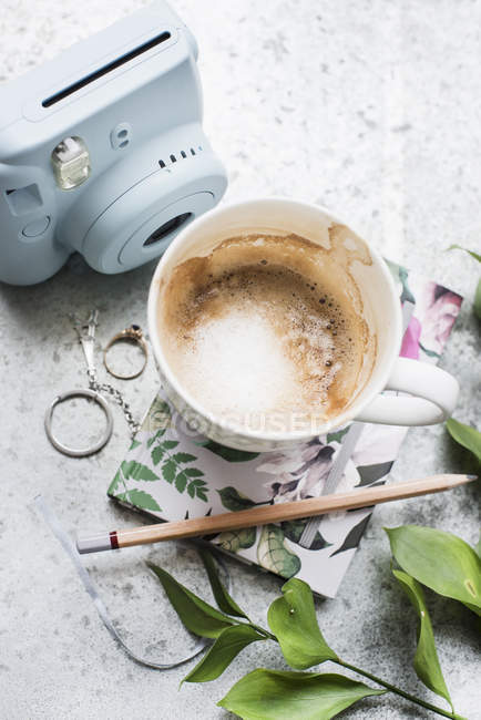 Hochblicktasse Kaffee mit Notizbuch und Filmkamera auf hellem Tisch — Stockfoto