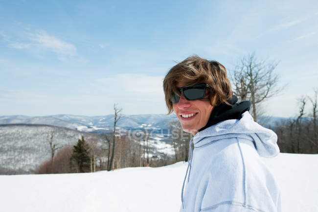 Jovem sorrindo para a câmera na paisagem nevada — Fotografia de Stock
