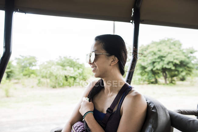 Vista laterale di Giovane turista di sesso femminile guardando fuori autobus in viaggio gioco drive, Botswana, Africa — Foto stock