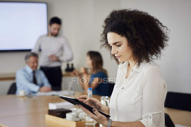 Femme d'affaires au bureau en utilisant une tablette numérique tout en rencontrant — Photo de stock