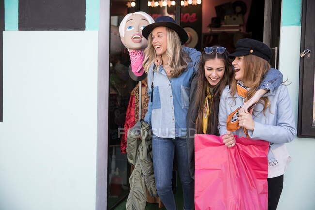 Amigos saliendo de la tienda de ropa sonriendo - foto de stock