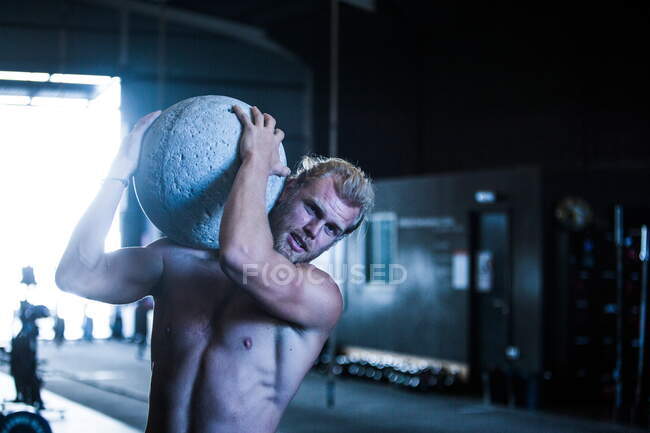 Hombre ejercitándose en el gimnasio, utilizando piedra atlas - foto de stock