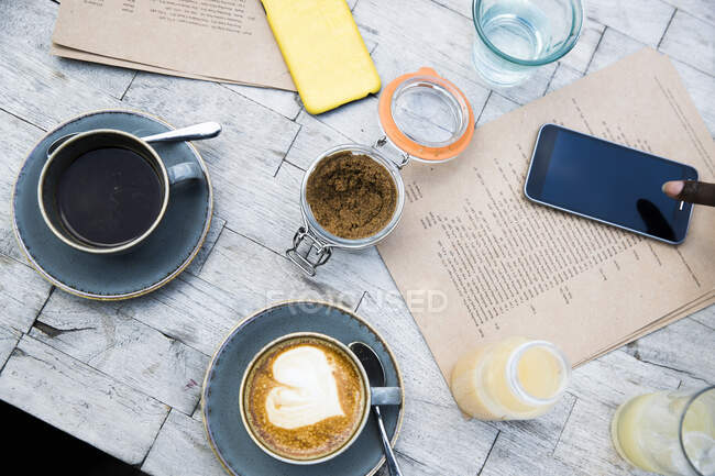 Café, teléfono móvil, menú en mesa de madera - foto de stock