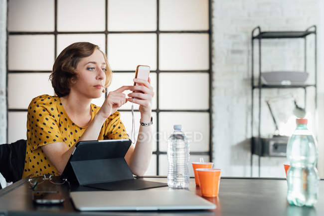 Empresária usando smartphone na mesa de escritório — Fotografia de Stock