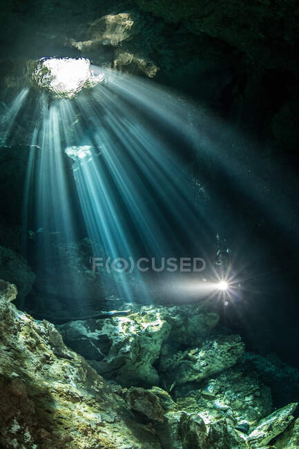 Immersioni subacquee maschili nel fiume sotterraneo (cenote) con raggi solari e formazioni rocciose, Tulum, Quintana Roo, Messico — Foto stock