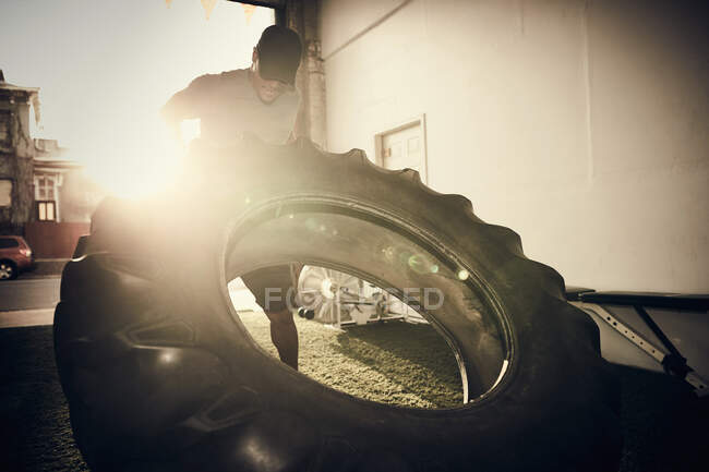 Mann hebt großen Reifen — Stockfoto