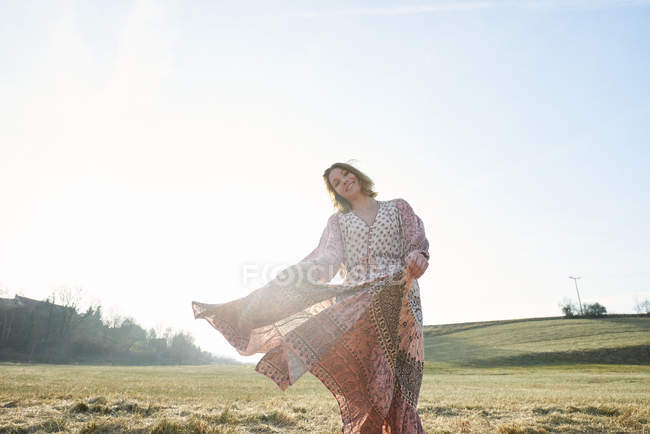 Hippy style woman dancing in sunlit field — Stock Photo