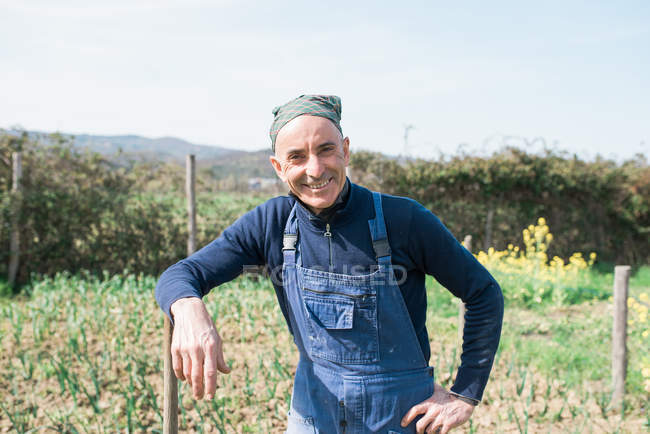 Людина в овочевому саду посміхається на камеру — стокове фото