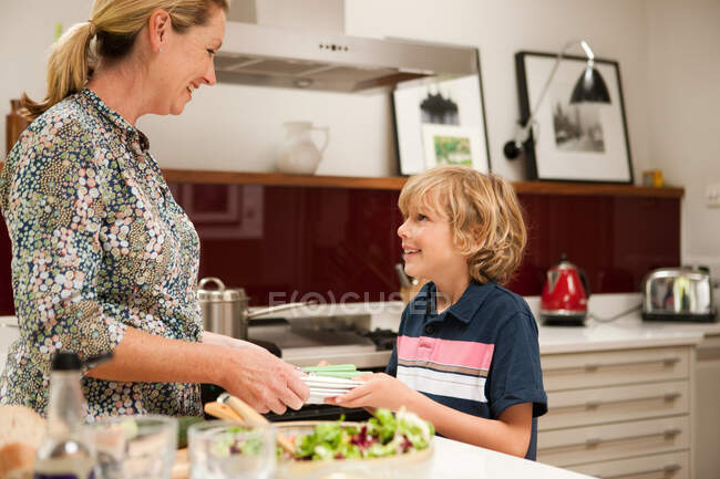 Son helping to carry napkins for mother, in preparation for meal — Stock Photo