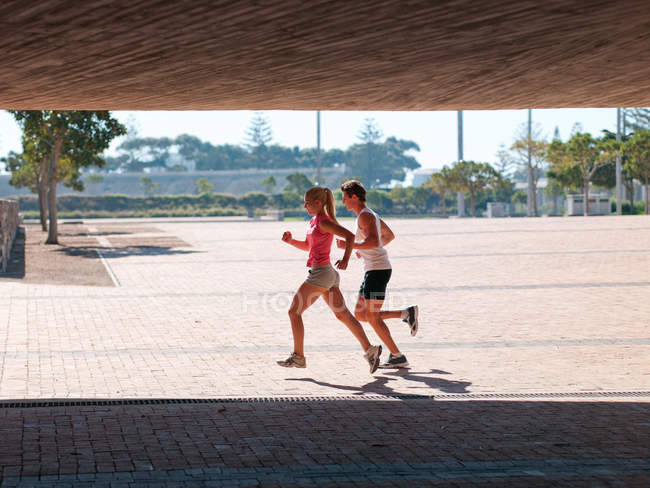 Молода пара працює в спортивному одязі на відкритому повітрі вдень — стокове фото