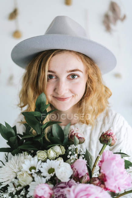 Портрет усміхненої жінки, що тримає купу квітів, дивлячись на камеру — стокове фото