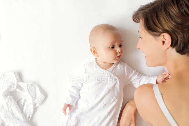 Overhead view of mother and baby boy lying face to face on white background — Stock Photo