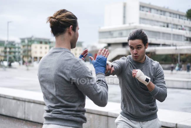 Boxeadores gemelos practicando golpes al aire libre - foto de stock