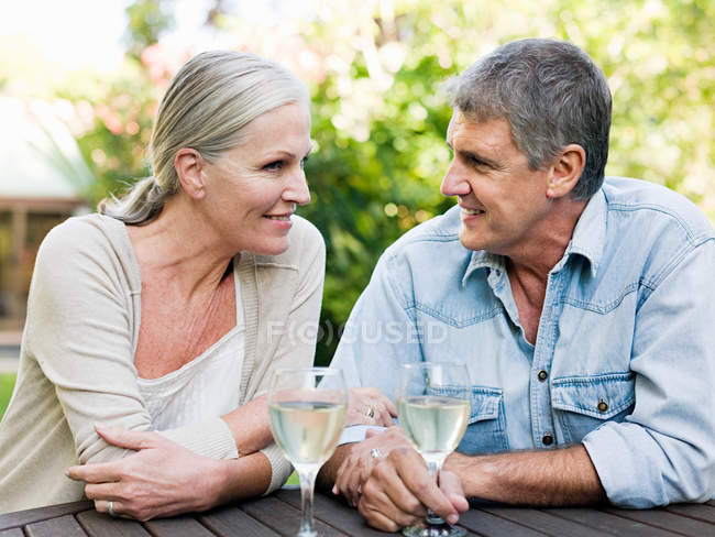 Зрелая пара с вином, отдыхающая в саду — стоковое фото