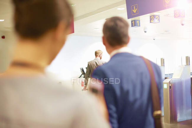 Empresarios y mujeres caminando por la puerta de seguridad en el aeropuerto - foto de stock