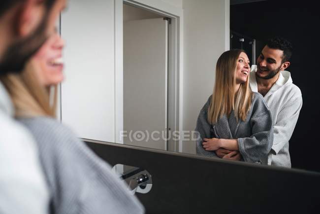 Дзеркальне зображення пари, що обіймається у ванній кімнаті — стокове фото