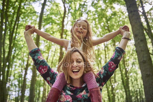 Mulher dando filha um passeio de ombro na floresta — Fotografia de Stock