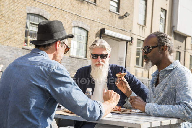 Amigos comiendo pizza al aire libre, Londres, Reino Unido - foto de stock