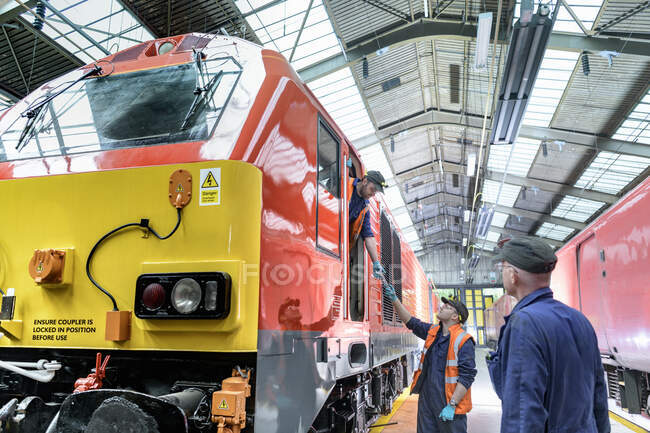 Engineers with refurbished locomotive in train engineering factory — Stock Photo