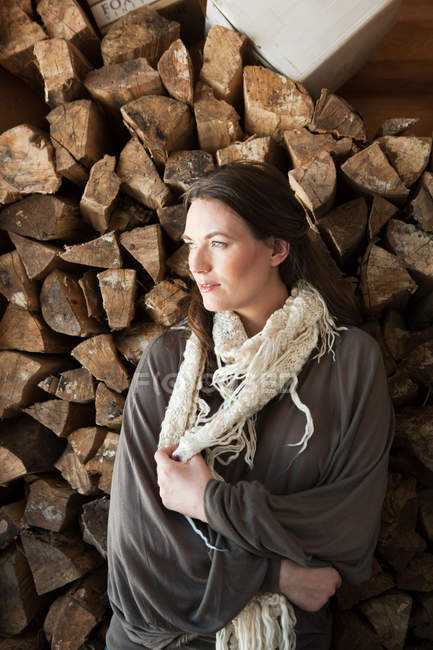 Woman in front of logs looking away — Stock Photo