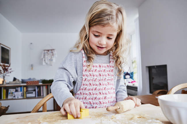 Young girl making cookies with cookie cutter — Stock Photo