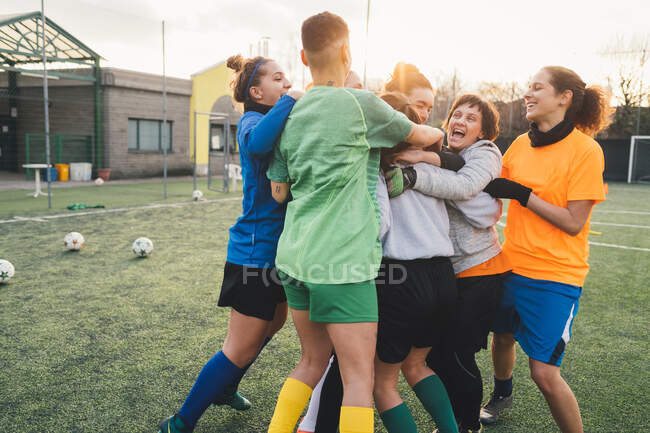 Jugadores de fútbol jubilosos y abrazándose en el campo - foto de stock