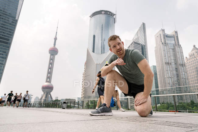 Young male runner taking break in Shanghai financial center, Shanghai, China — Stock Photo