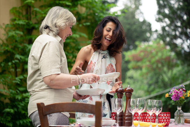 Mother and adult daughter setting table for family meal — Stock Photo