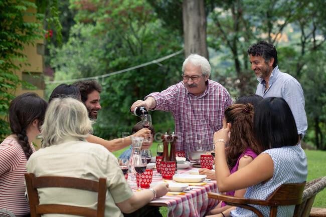 Senior homme verser du vin au repas de famille — Photo de stock