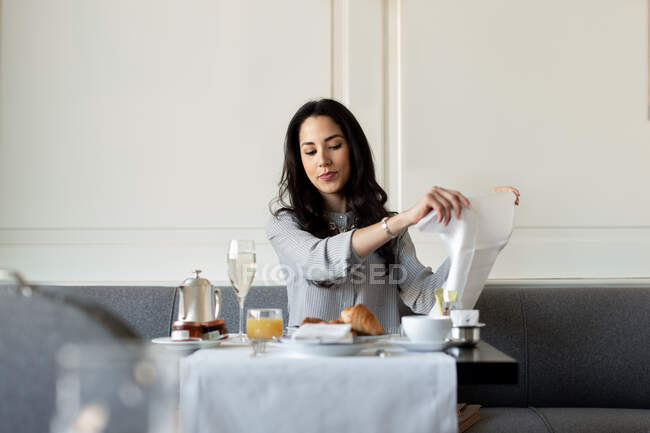 Jovem mulher preparando guardanapo enquanto toma café da manhã champanhe no hotel boutique na Itália — Fotografia de Stock
