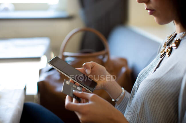 Foto recortada de mujer joven con tableta digital haciendo pago de crédito electrónico mientras desayunaba en un hotel boutique en Italia - foto de stock